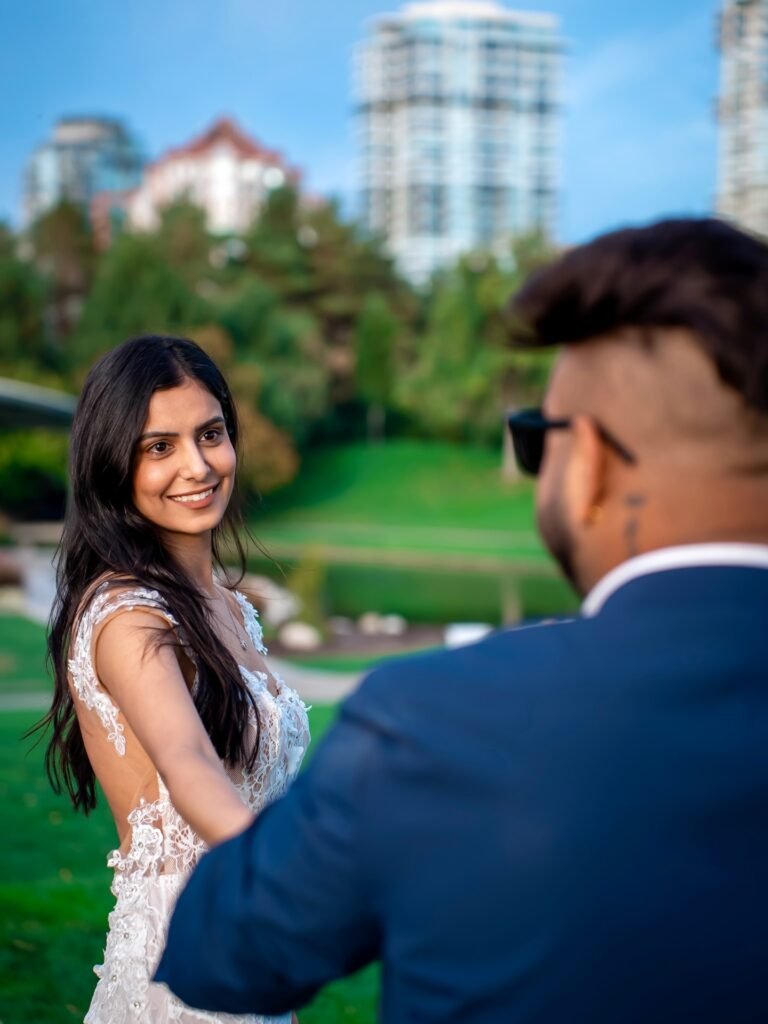 Bride smiling at camera with groom in park, Kelowna wedding photoshoot