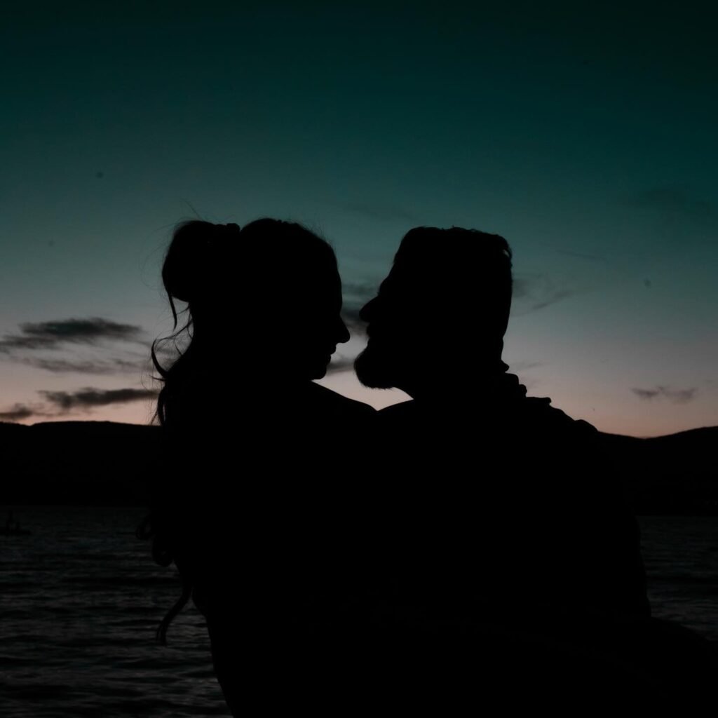 Couple silhouette facing each other at sunset over water, Kelowna couple photography
